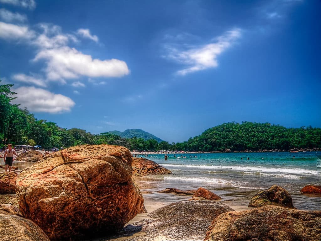 Uma das melhores praias em Ubatuba para famílias com crianças, a praia Domingas Dias pode ser vista na foto, com vegetação, mar e pedras. Foto de Rafael Vianna via Flickr