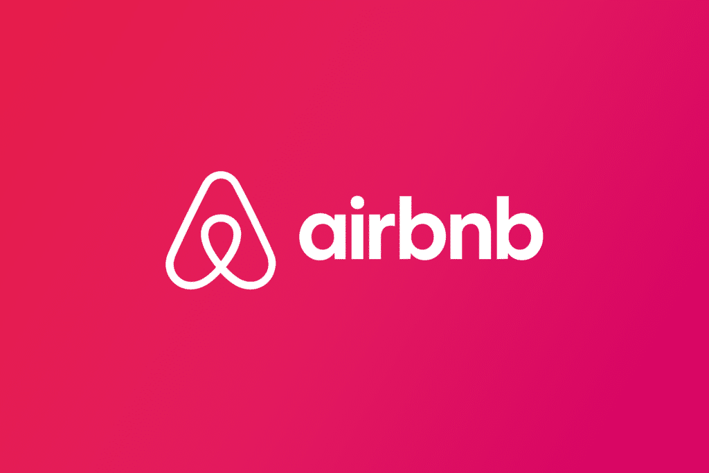 Logo do airbnb com o fundo rosa e desenho branco. No meio da imagem, tem o logo do site e ao lado a escrita "Airbnb"
