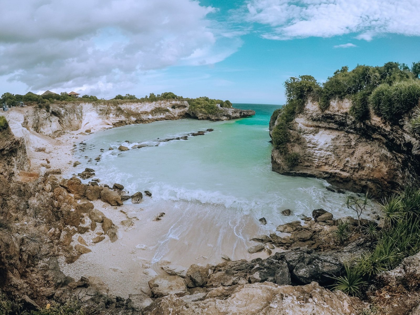 Vista de cima da Nusa Ceningan, em Bali na Indonésia, com mar azul claro, areias brancas e rochas em volta da praia durante o dia. 
