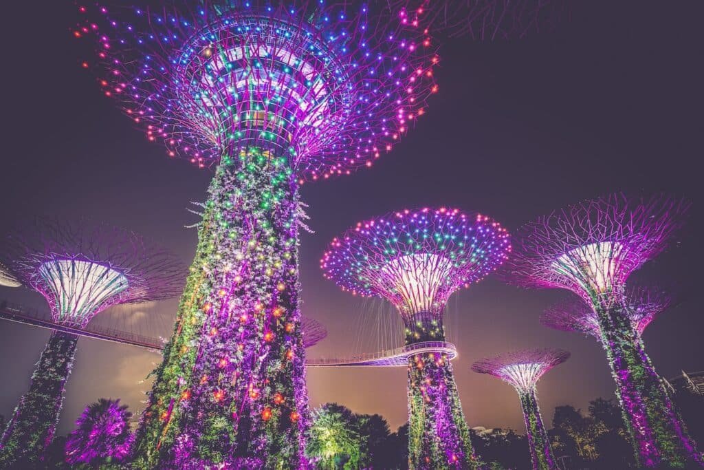 Altas estruturas artificiais de árvores iluminadas com luzes coloridas à noite nos Jardins da Baía, em Singapura.